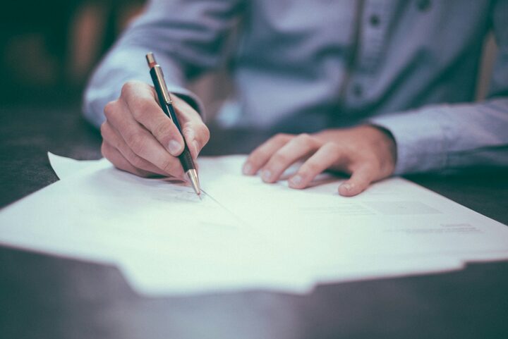 Desk paperwork and a pen — compliance review is a document and ticket process, not an on-chain bypass.
